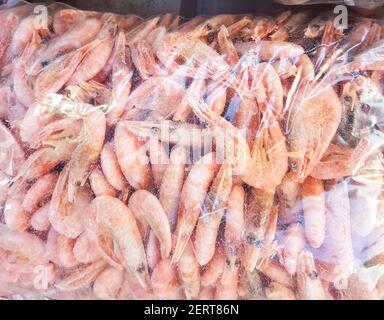 Zwei große Plastiktüten mit gefrorenen rohen und gekochten Garnelen, auf der Theke des Fischmarktes. Stockfoto