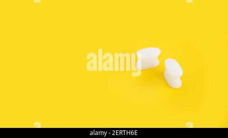 Weißer Silikon-Fingerteiler auf gelbem Hintergrund. Prävention und Behandlung von Hallux Valgus Stockfoto