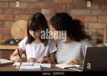 Junge Latino Mutter helfen Tochter mit Schulvorbereitung Stockfoto