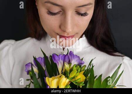 Junge Frau und Blumenstrauß von Freesia Blumen im Studio Stockfoto