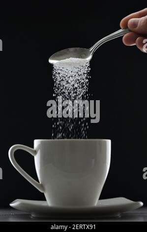 Tee Tasse oder Kaffee und Gießen Zuckerlöffel auf schwarz Hintergrund Stockfoto