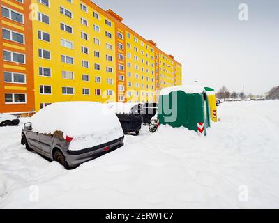 Mülltonnen und Container für sortierte Abfälle am Rande des Parkplatzes vor großen Fertighäusern. Der Rand der Wohnanlage an Stockfoto