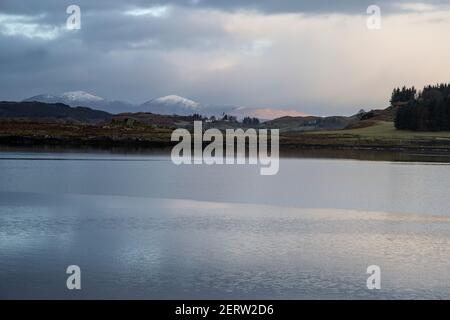 Blick nach Westen zu den schneebedeckten Gipfeln von Caddleton in Schottland gegenüber in Richtung Siel und Mull aus dem schottischen Westen Küste im Winter Stockfoto