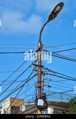 Ein Laternenpfosten mit vielen Drähten. Ein sonniger Herbsttag ist ein Seitenblick. Stockfoto