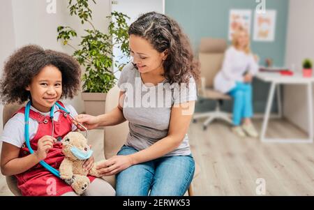 Kleines Mädchen mit ihrer Mutter während eines Besuchs bei Kinderarzt. Beratung mit einem Kinderarzt Stockfoto