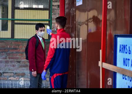 Ein Schüler wird vor dem Betreten des Gebäudes auf seine Temperatur überprüft, da die Schulen nach einem Jahr Pause aufgrund der Coronavirus-Pandemie in Srinagar wieder eröffnet wurden.die Schulen in Kaschmir haben für Schüler der Klassen 9 bis 12 wieder geöffnet, nachdem sie wegen des Coronavirus fast ein Jahr lang geschlossen wurden Pandemie. Noch bevor die Covid-19 ihre Schließung erzwang, blieben die Bildungseinrichtungen wegen der Sicherheits- und Kommunikationsknappheiten nach der Aufhebung des Artikels 370 am 5. August 2019 fast ein Jahr geschlossen. Inzwischen nahmen Jammu und Kaschmir 97 neue Covid-19 Fälle auf, die die infe nahmen Stockfoto