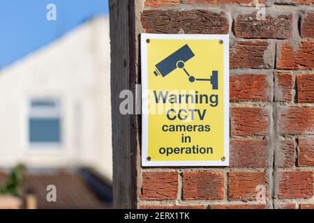 Ein CCTV-Warnschild an einer Ziegelwand außerhalb eines Haus Stockfoto