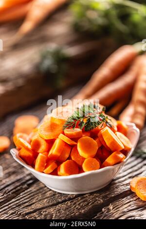 In Scheiben geschnittene Stücke von Karotte in einer Schüssel und eine frische Ein paar Karotten im Hintergrund Stockfoto