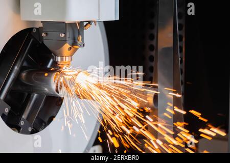 Laserschneidmaschine arbeitet mit zylindrischem Metallwerkstück mit Funken Stockfoto