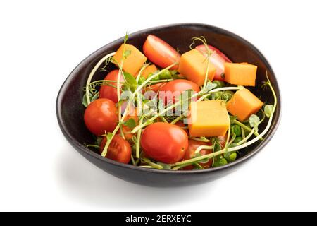 Vegetarischer Gemüsesalat aus Tomaten, Kürbis, mikrogrüne Erbsensprossen isoliert auf weißem Hintergrund. Seitenansicht, Nahaufnahme. Stockfoto
