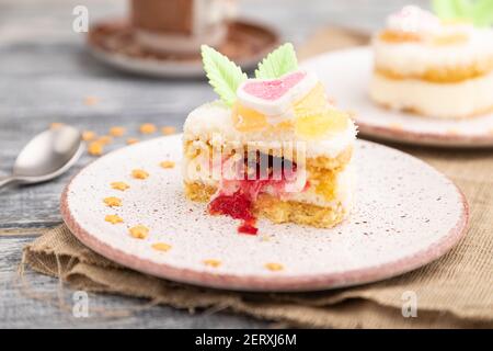 Dekorierter Kuchen mit Milch und Kokosnusscreme mit einer Tasse Kaffee auf einem grauen Holzhintergrund und Leinentextilien. Seitenansicht, Nahaufnahme, selektiver Fokus. Stockfoto