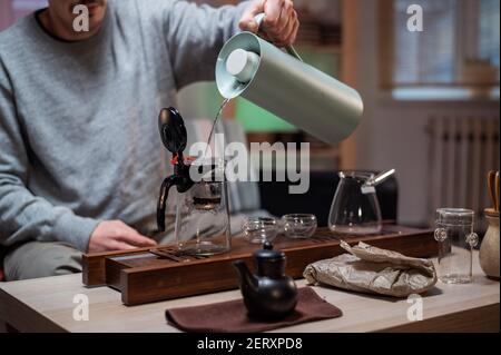 Ein wahrer Meister traditioneller chinesischer Zeremonien Braut gealterten schwarzen Tee, indem er heißes Wasser in die Teekanne gießt. Tea Party in den Komfort von zu Hause. Stockfoto