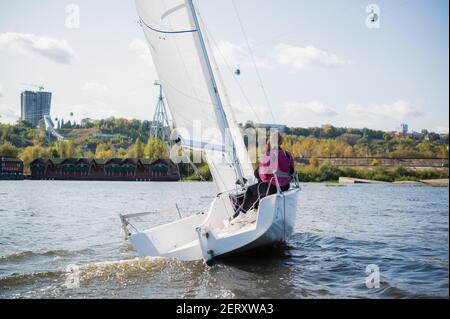 Eine gemischte Crew einer Sportyacht nimmt an Segelwettbewerben auf dem Fluss Teil. Ein Mann und zwei Mädchen. Stockfoto