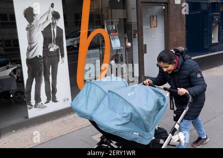 Am 26th. Februar 2021 schiebt eine Frau in London, England, einen DoppelZwillingswagen an einem Schaufenster des Barbershops vorbei, das an der Londoner Mauer in der City of London, dem Finanzviertel der Hauptstadt, ausgestellt ist. Stockfoto