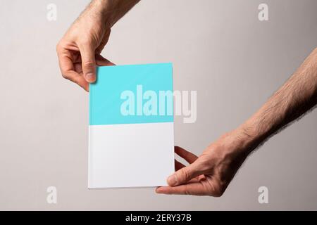 Männliche Hand hält einen geschlossenen Buch-Katalog mit leerem Einband, editierbare Modell-up-Serie Vorlage bereit für Ihr Design, Buchcover Auswahlpfad enthalten. Stockfoto