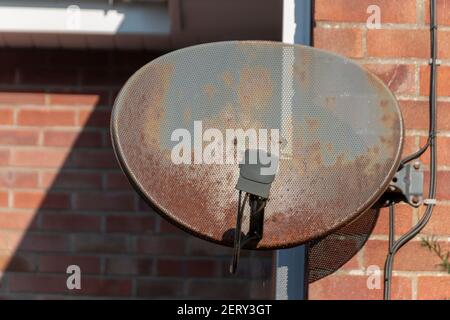 Eine Nahaufnahme einer alten verrosteten Satellitenschüssel An einer Ziegelwand befestigt Stockfoto