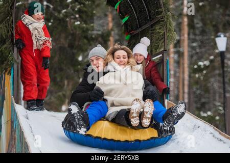 Eltern kauften ihre Kinder Schläuche und jetzt die ganze Familie Fahren Sie die Eisrutsche hinunter Stockfoto