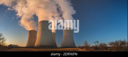 Temelin, Tschechische republik - 02 28 2021: Kernkraftwerk Temelin, dampfende Kühltürme in der Landschaft bei Sonnenuntergang Stockfoto