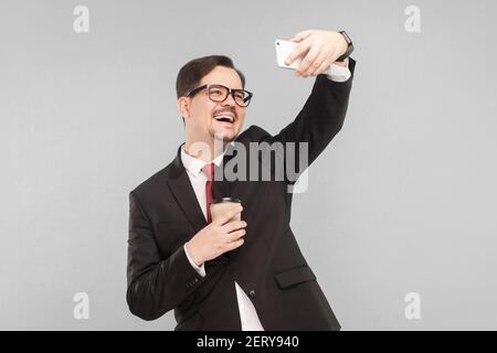 Business, Gadgets, Technologien. Business-Mann toothy lächeln, machen Foto. Indoor, Studioaufnahme, isoliert auf grauem Hintergrund Stockfoto