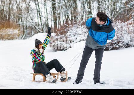 Liebevolles lächelndes Paar umarmt am Winterschneetag Stockfoto