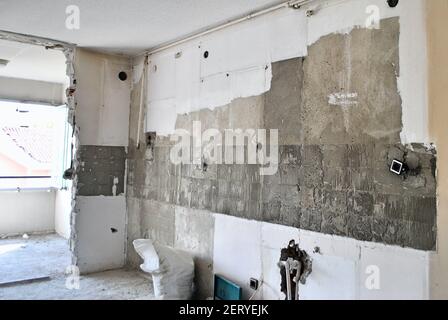 Küchenwand während der Umbauarbeiten ohne Tür, Fliesen und Wasserhahn. Renovierung des Hauses verbessert. Hausreparatur Stockfoto