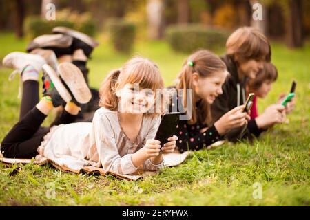 Outdoor-Porträt von kleinen Mädchen und Jungen spielen mit Handys. Hochwertige Fotos Stockfoto