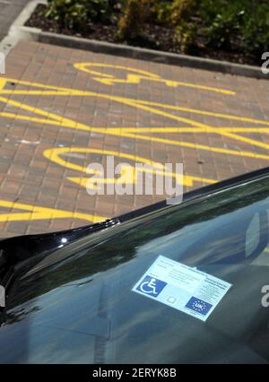 Eine Windschutzscheibe mit einem Behindertenausweis und Markierungen für Inhaber von Behindertenausweisen nur auf einem Parkplatz in Schottland, Großbritannien Stockfoto