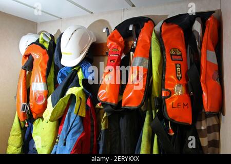 Ausrüstung einschließlich Schwimmwesten und Hüte von Fischern getragen Aufhängen in einem Trawler Stockfoto