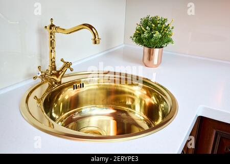 Küche luxuriöse Innenausstattung mit goldenen Messing Waschbecken und Wasserhahn doppelt Armatur in modernem Design mit Steinmarmor-Steinzeug Arbeitsplatte Stockfoto