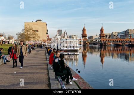 Vorfrühling in Berlin Mitte Februar 2021 , Spreeufer bei der East Side Gallery , Spaziergänger, Promenade, Hostel Boat, Stockfoto