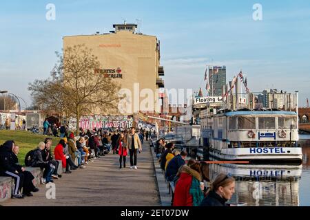 Vorfrühling in Berlin Mitte Februar 2021 , Spreeufer bei der East Side Gallery , Spaziergänger, Promenade, Hostel Boat, Stockfoto