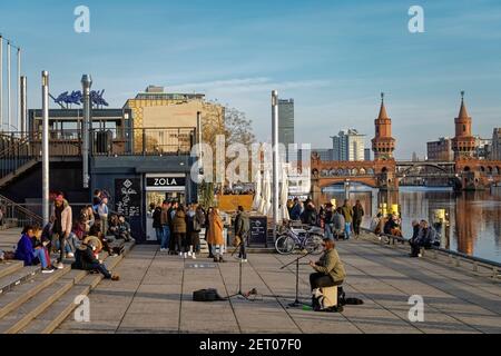 Vorfruehling in Berlin Mitte Februar 2021 , Spreeufer bei der East Side Gallery , Spaziergaenger, Promenade, Oberbaumbrücke, Spree, Strassenmusiker Stockfoto