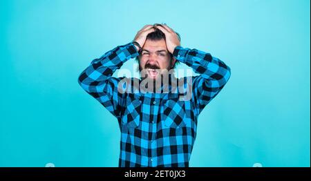 Schmerzen im Kopf. Modern aussehende bärtige Hipster hat Kopfschmerzen. Healthcare-Konzept. Brutal schöner Mann mit Schnurrbart. Reifen Friseur auf blauem Hintergrund. Männlichkeit und Charisma. oh nein Stockfoto