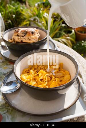 Frühstück im Freien mit Schale Cornflakes und kalte Milch werden Über Großbritannien gegossen Stockfoto