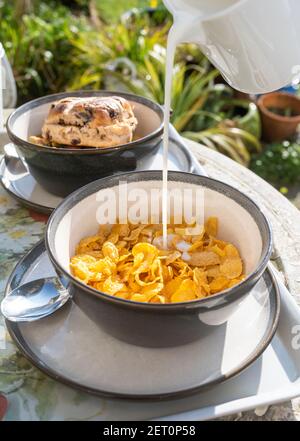 Frühstück im Freien mit Schale Cornflakes und kalte Milch werden Über Großbritannien gegossen Stockfoto