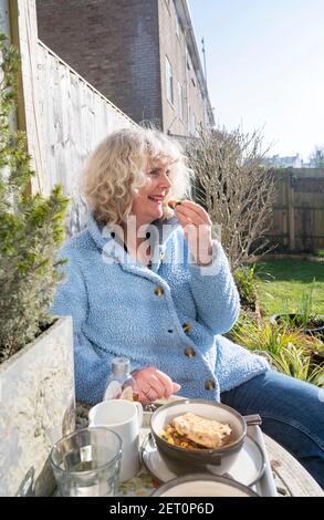 Frau essen heiße Cross Brötchen Frühstück im Freien Brighton UK auf Ein sonniger Morgen Stockfoto