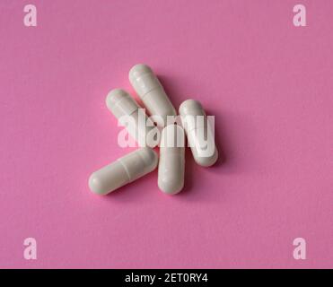 Weiße, große Kapseln, Pillen oder Tabletten auf einem rosa Hintergrund Stockfoto
