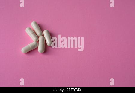 Weiße, große Kapseln, Pillen oder Tabletten auf einem rosa Hintergrund Stockfoto