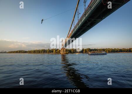 Man Bungee Jumping auf Parkovy Fußgängerbrücke über Dnjepr Fluss - Kiew, Ukraine Stockfoto