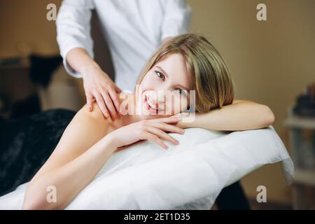 Junge Frau genießt eine Rückenmassage. Professioneller Masseur behandelt weibliche Patienten. Entspannung, Schönheit, Körper und Gesicht Behandlung Konzept Stockfoto