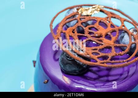 Schönes Dekor aus Schokolade und Kakao auf Heidelbeerkuchen. Blauer Hintergrund Stockfoto