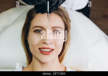 Anti-Aging-Injektionen Schönheitsbehandlung. Nahaufnahme des Gesichts einer jungen Frau, die auf dem Rücken liegt und eine Injektion bekommt Stockfoto