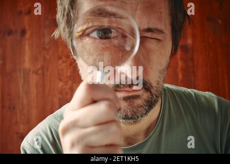 Neugieriger Mann durch Lupe mit intensivem Wunsch zu schauen Wissen und verstehen Stockfoto