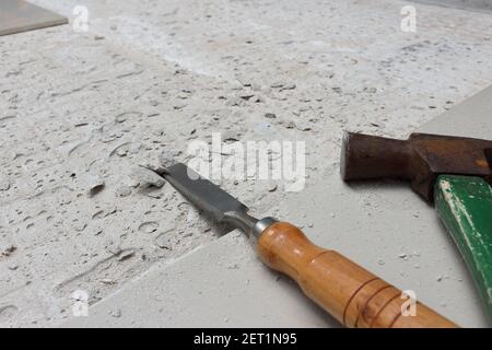 Ein Hammer zum Hämmern von Nägeln und ein Holzmeißel wird neben dem neu gefliesten Bereich platziert. Stockfoto