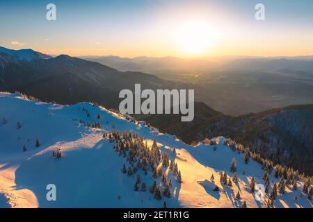 Luftaufnahme der Winterlandschaft Wald mit schönen Sonnenuntergang in der Ferne. Stockfoto