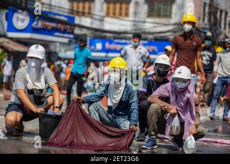 Yangon, Myanmar. März 2021, 01st. Anti-Militärputsch Demonstranten, die während einer Demonstration gegen den Militärputsch nasse Kleidung benutzen, um Tränengaskanister zu werfen.die Polizei in Myanmar feuerte am Montag Gummigeschosse, Tränengas und Schallbomben auf friedliche Anti-Militärputsch-Demonstranten. Mehrere wurden verhaftet und verletzt, aber die genaue Zahl ist noch unklar. Kredit: SOPA Images Limited/Alamy Live Nachrichten Stockfoto
