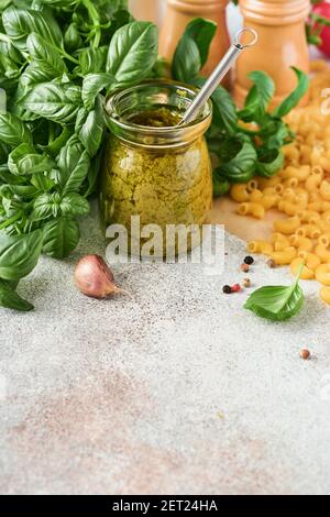 Chifferi rigati klassische rohe Pasta in braunem Papier auf hellem Holztischhintergrund mit Basilikum und Öl. Stockfoto