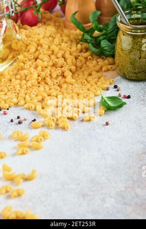 Chifferi rigati klassische rohe Pasta in braunem Papier auf hellem Holztischhintergrund mit Basilikum und Öl. Stockfoto
