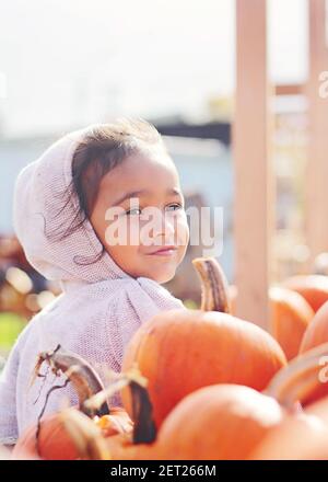 Porträt eines lächelnden Mädchens mit windgepeitschten Haaren neben Kürbissen, Washington, USA Stockfoto