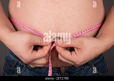 Fettleibigkeit ein Mann misst seinen großen Bauch mit einem Zentimeter, falsch Lifestyle Stockfoto